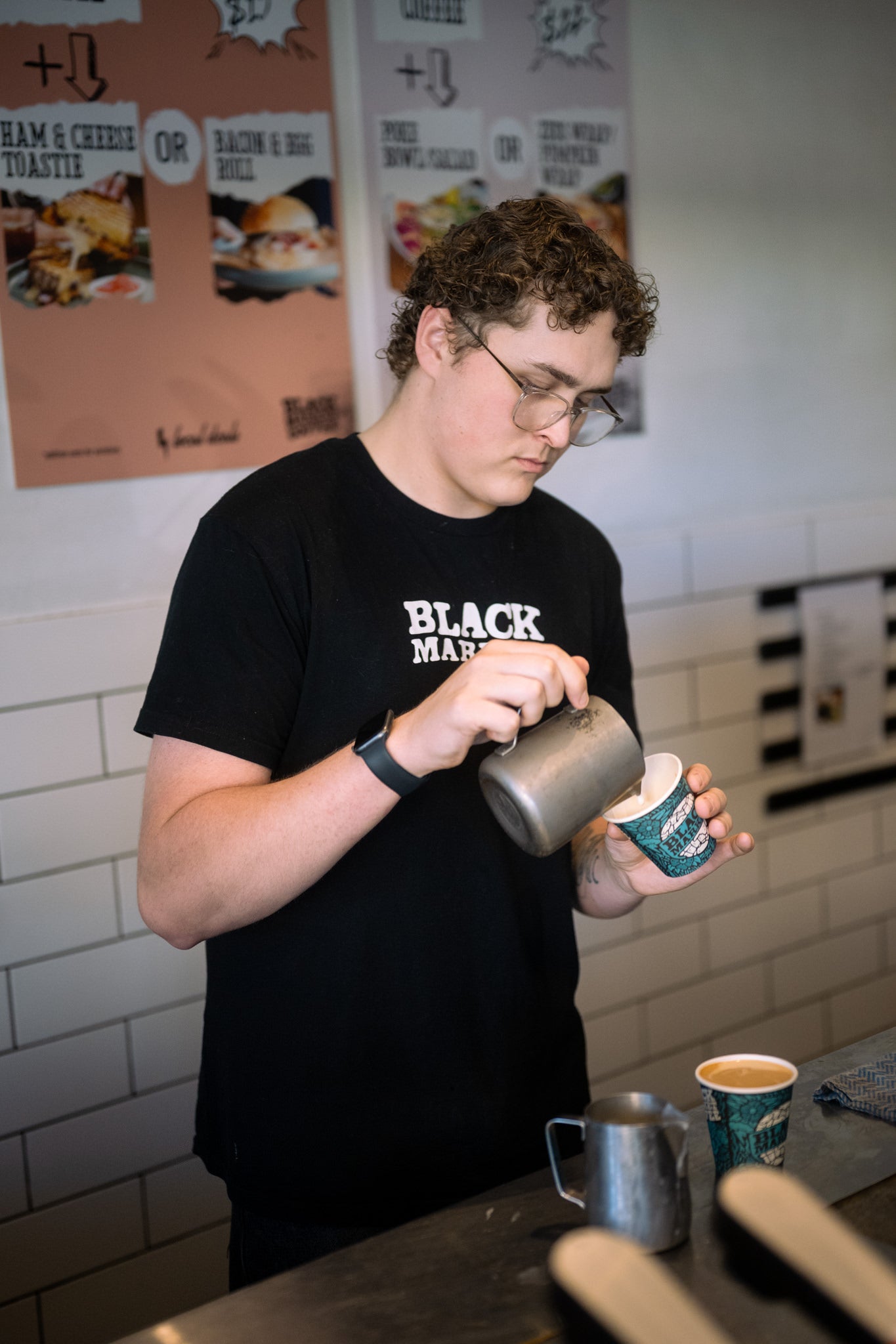 Barista pouring latte art at Black Market Training Sydney roastery studio