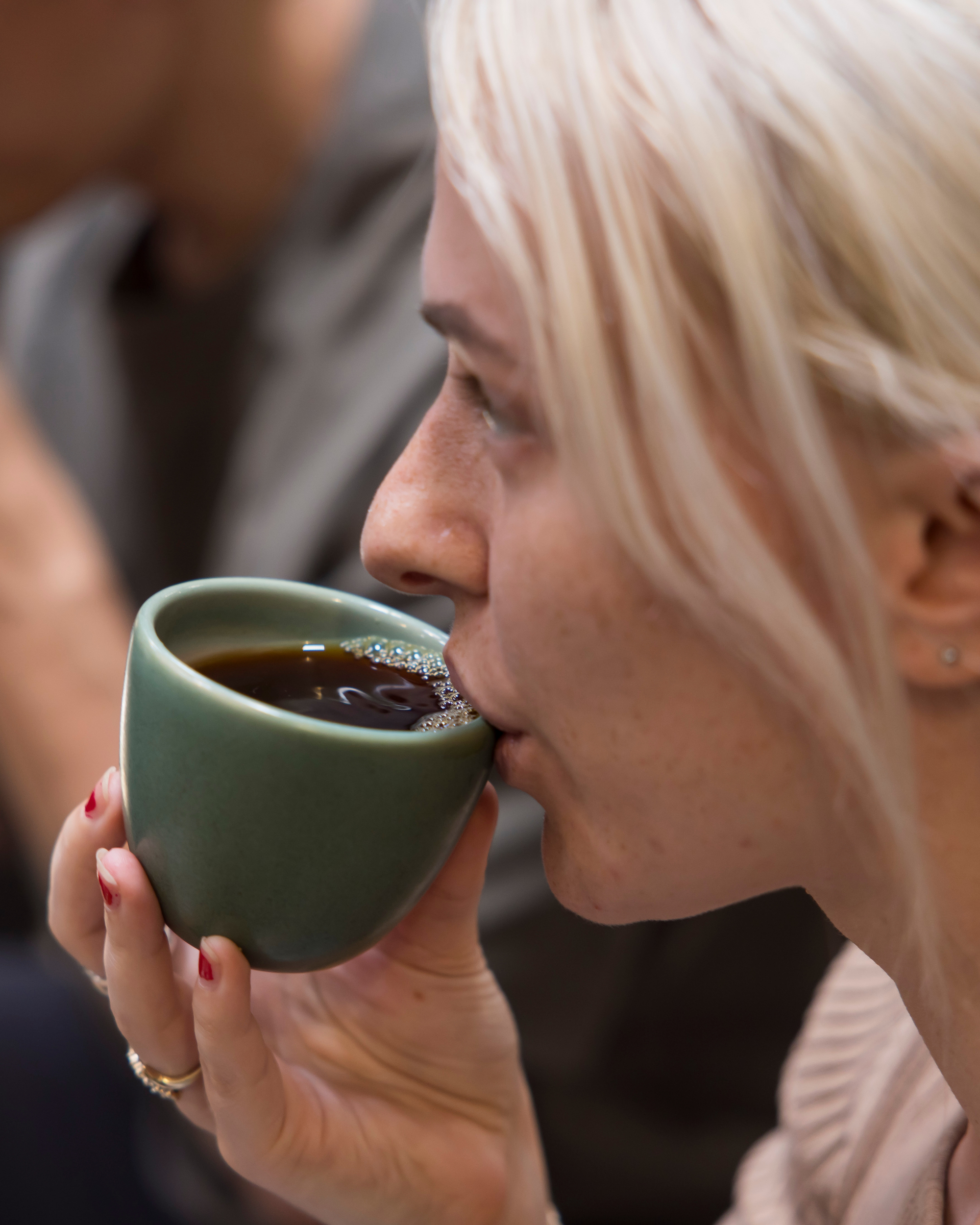 Woman drinking from a green ceramic cup, learning coffee flavour and origin 